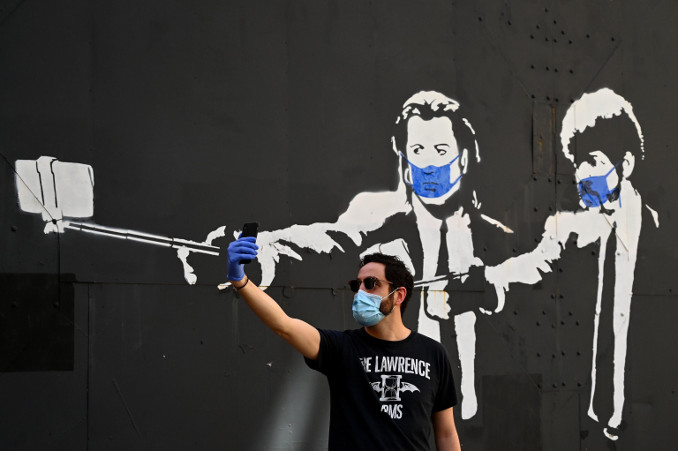 Selfie davanti a un murale di Pulp Fiction in versione emergenza coronavirus