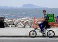 Rider effettua consegne in bicicletta sul lungomare di Napoli