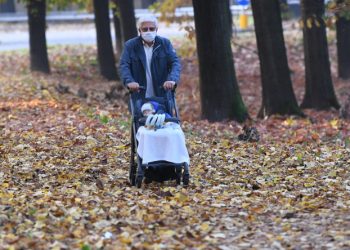 Nonno e nipote neonato passeggiano in un parco di Milano durante il lockdown