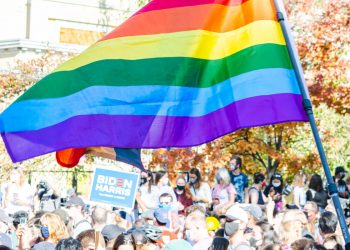 Manifestazione con bandiera arcobaleno e manifesto pro Biden