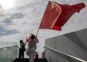 Una donna festeggia a Hong Kong con la bandiera cinese l'anniversario dell'handover