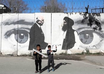 Bambini davanti a un murale che celebra gli accordi di pace di Doha tra Usa e Afghanistan