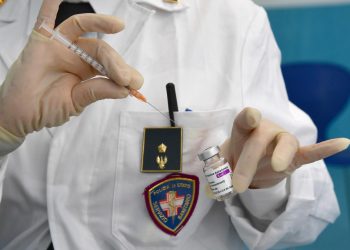Agente di polizia somministra vaccino AstraZeneca