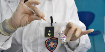 Agente di polizia somministra vaccino AstraZeneca