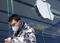 Un ragazzo cinese guarda l'iPhone mentre passa davanti a un negozio della Apple in Cina