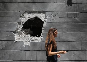 Donna davanti a un muro colpito da un missile ad Askelon, Israele