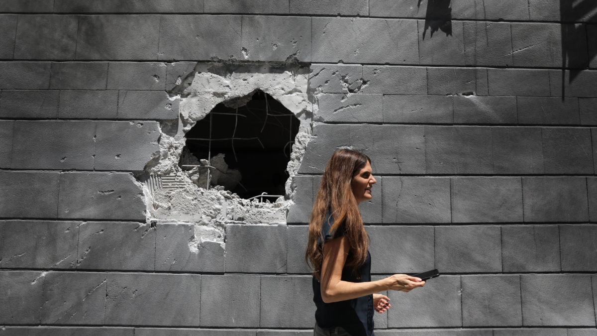 Donna davanti a un muro colpito da un missile ad Askelon, Israele