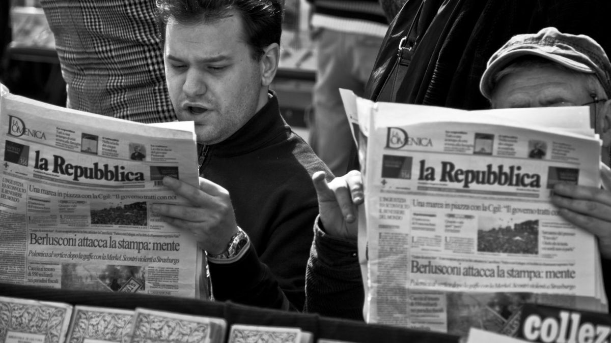 Due uomini sfogliano il quotidiano La Repubblica