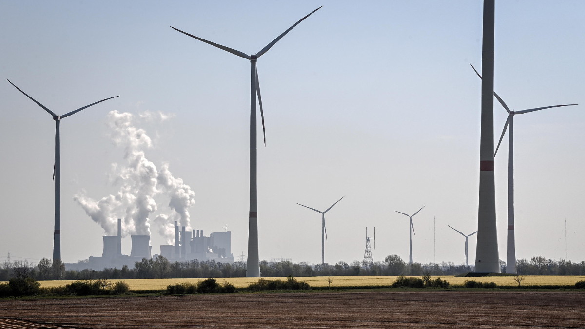 Centrale a carbone sullo sfondo della distesa di pale di un parco eolico