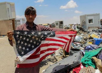 Un giovane in Afghanistan mostra la bandiera degli Usa