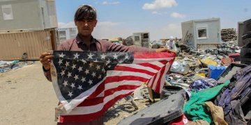Un giovane in Afghanistan mostra la bandiera degli Usa
