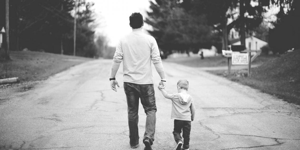 Un padre cammina insieme al figlio tenendolo per mano