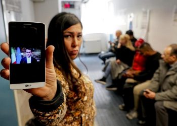 Una donna in fila per fare domanda per il reddito di cittadinanza mostra un telefonino con la foto del ministro Luigi Di Maio