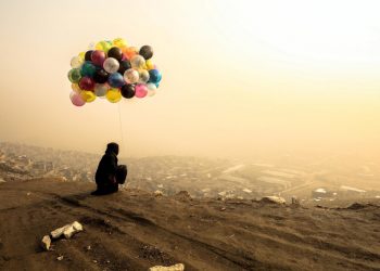 Venditrice di palloncini davanti a Kabul avvolta nella nebbia