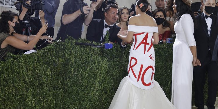 Alexandria Ocasio-Cortez impacchettata nel suo tubino "Tax the Rich" sul red carpet del Met in compagnia della stilista Aurora James (foto Ansa)