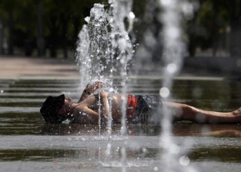 Un uomo sotto l'acqua di una fontana a Cordoba