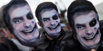 Manifestanti in piazza indossano maschere di Jair Bolsonaro rappresentato come un teschio per protestare contro il presidente del Brasile (foto Ansa)