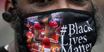 Un uomo indossa una mascherina con la foto di Colin Kaepernick durante una manifestazione antirazzista nel 2020 in America (foto Ansa)