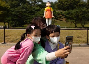 Selfie a Seoul davanti alla bambola-robot che in "Squid Game" uccide chi si muove durante "1, 2, 2, stella" (foto Ansa)