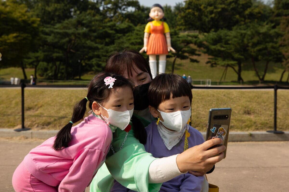 Selfie a Seoul davanti alla bambola-robot che in "Squid Game" uccide chi si muove durante "1, 2, 2, stella" (foto Ansa)
