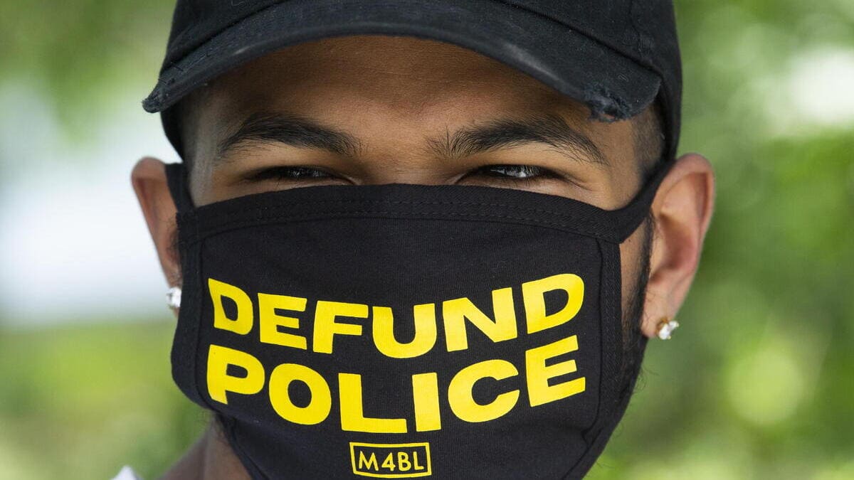 Un attivista pro Black Lives Matter promuove la campagna Defund police negli Usa