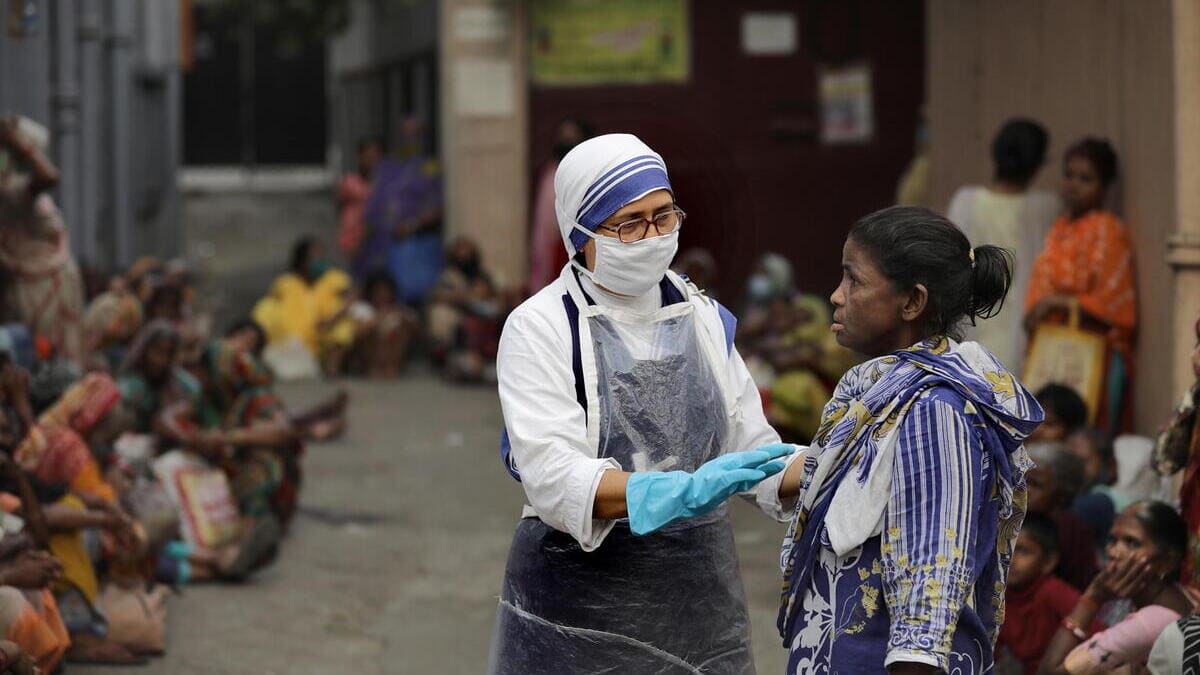 Una suora delle Missionarie della Carità fondate da Madre Teresa tra i poveri ammassati in cerca di aiuto davanti alla Casa di Calcutta 
