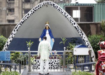 Un uomo prega davanti alla statua di Maria della chiesa cattolica di St. Leo a Lagos, Nigeria, 28 marzo 2021 (foto Ansa)