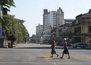 Due ragazze attraversano le strade deserte di Yangon, in Myanmar