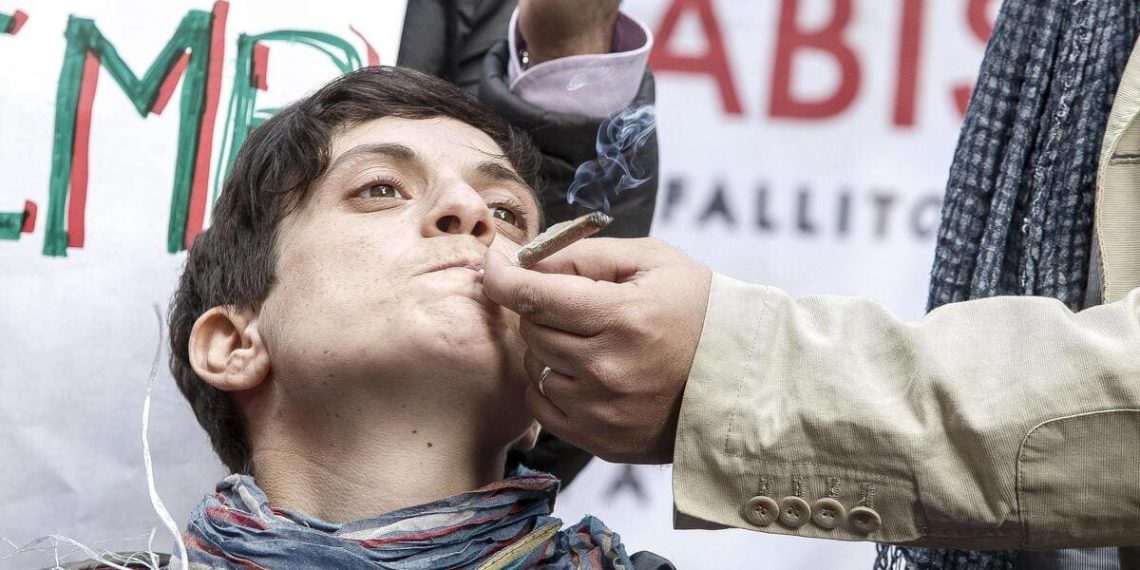 Un attivista radicale fuma uno spinello durante una manifestazione davanti a Montecitorio (foto Ansa)