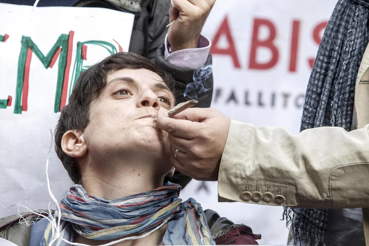Un attivista radicale fuma uno spinello durante una manifestazione davanti a Montecitorio (foto Ansa)