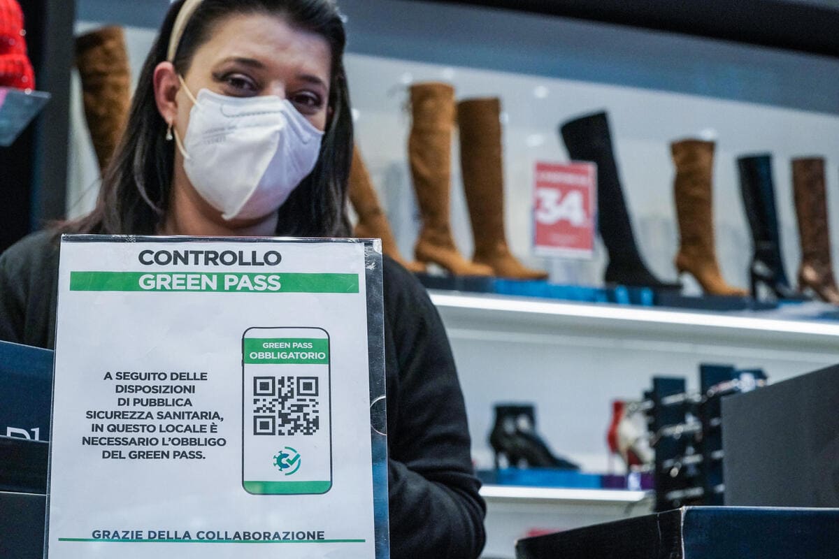 Una negoziante a Torino mostra il cartello del controllo del green pass