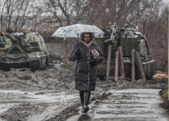 Una donna passeggia in Russia davanti ai carri armati destinati alla guerra in Ucraina