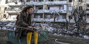 Una donna ucraina davanti a un edificio bombardato a Kiev