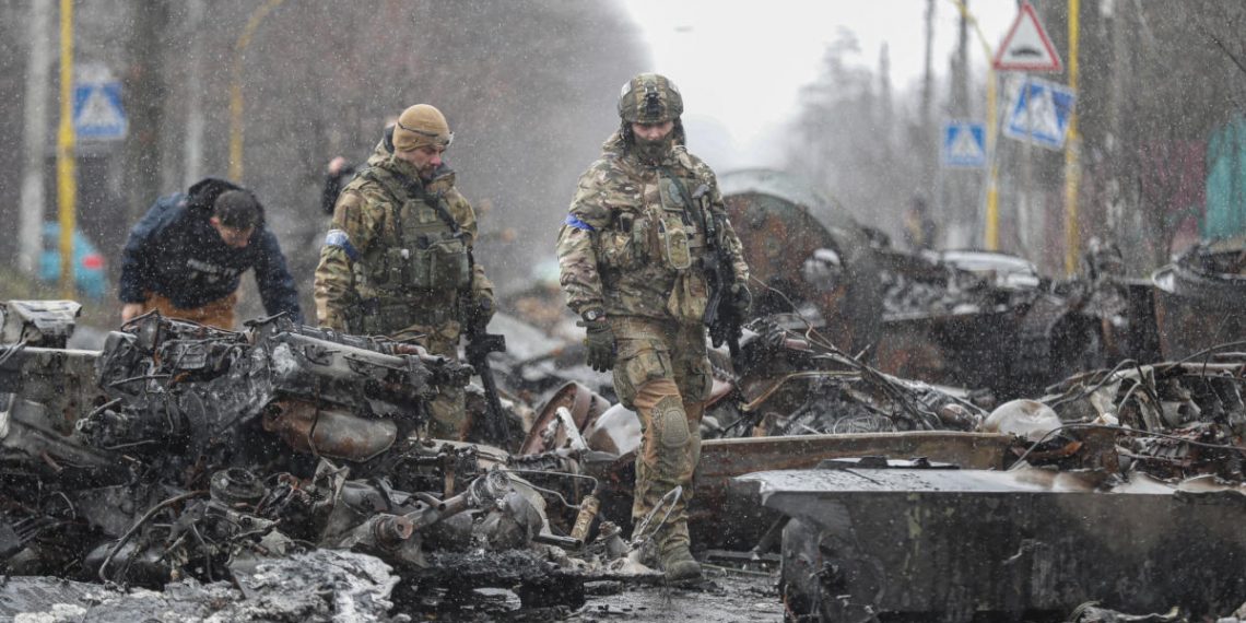 Soldati ucraini tra veicoli militari russi distrutti a Bucha