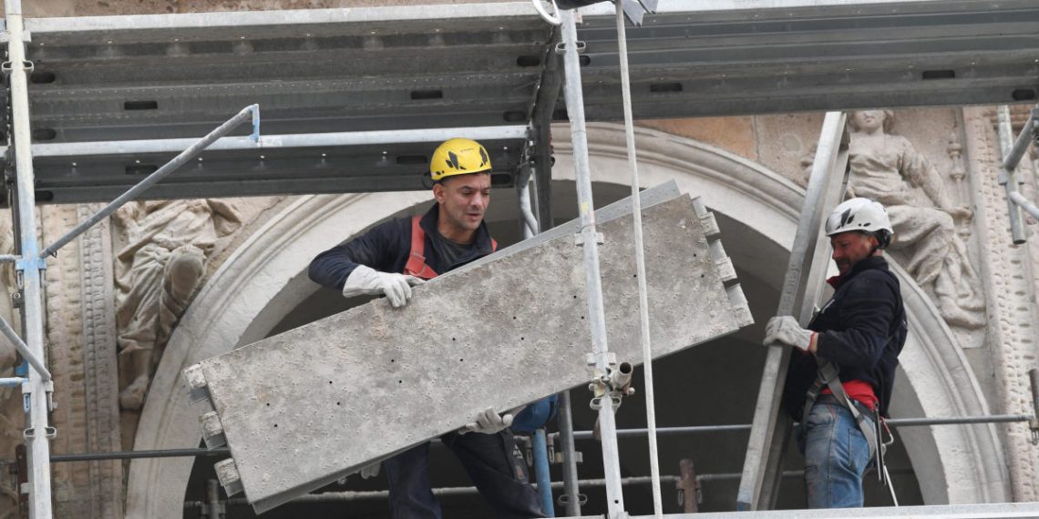 Operai smontano il ponteggio di un cantiere edile a Milano