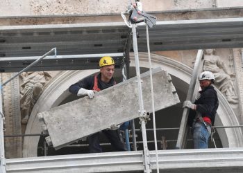 Operai smontano il ponteggio di un cantiere edile a Milano