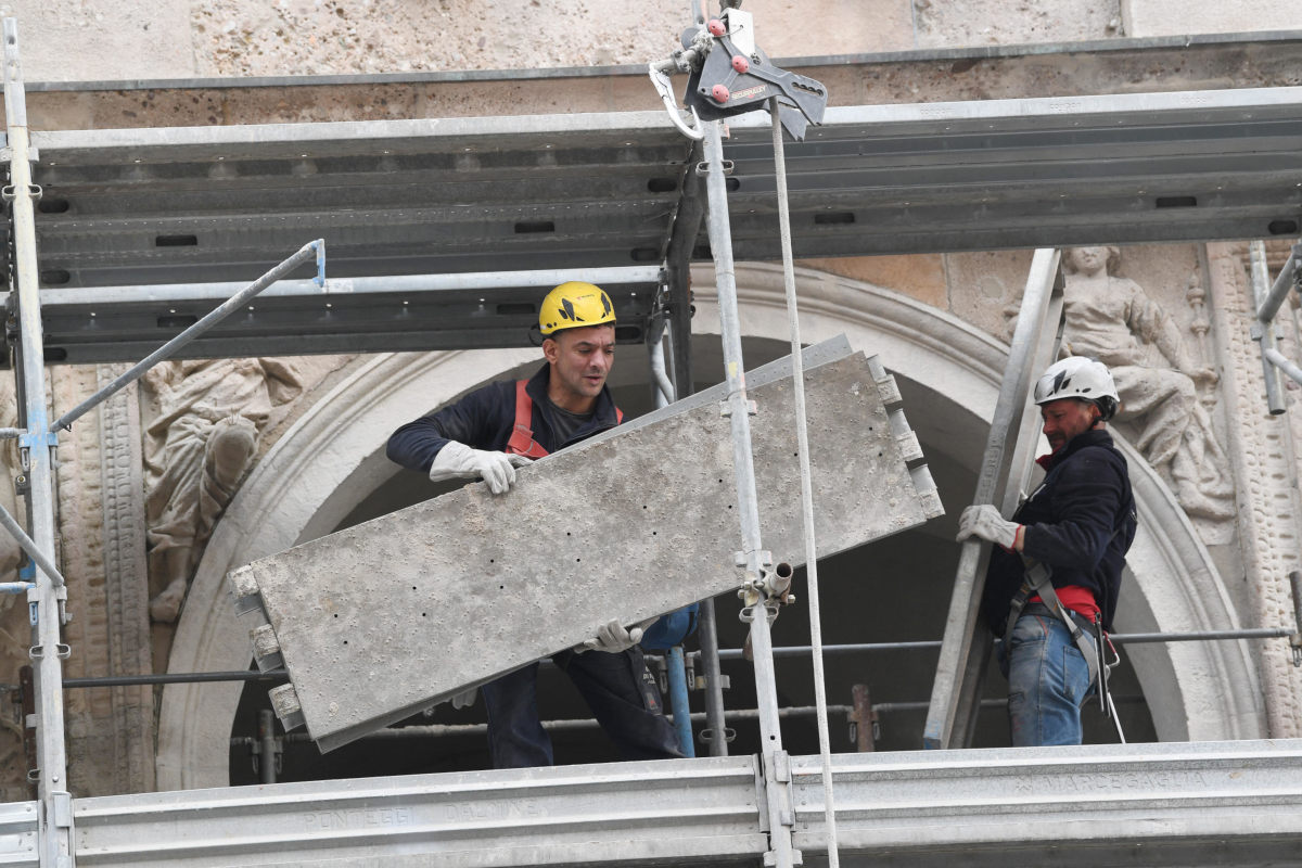 Operai smontano il ponteggio di un cantiere edile a Milano