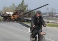 Un uomo in bicicletta oltrepassa un carro armato russo distrutto vicino a Kiev, in Ucraina