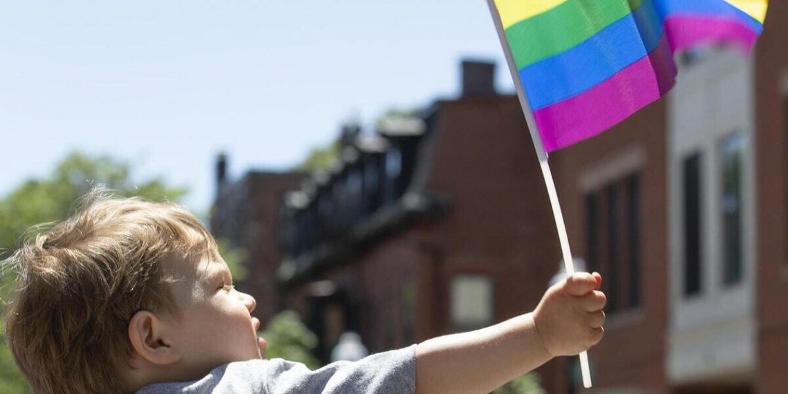Bambino con bandiera arcobaleno al gay pride