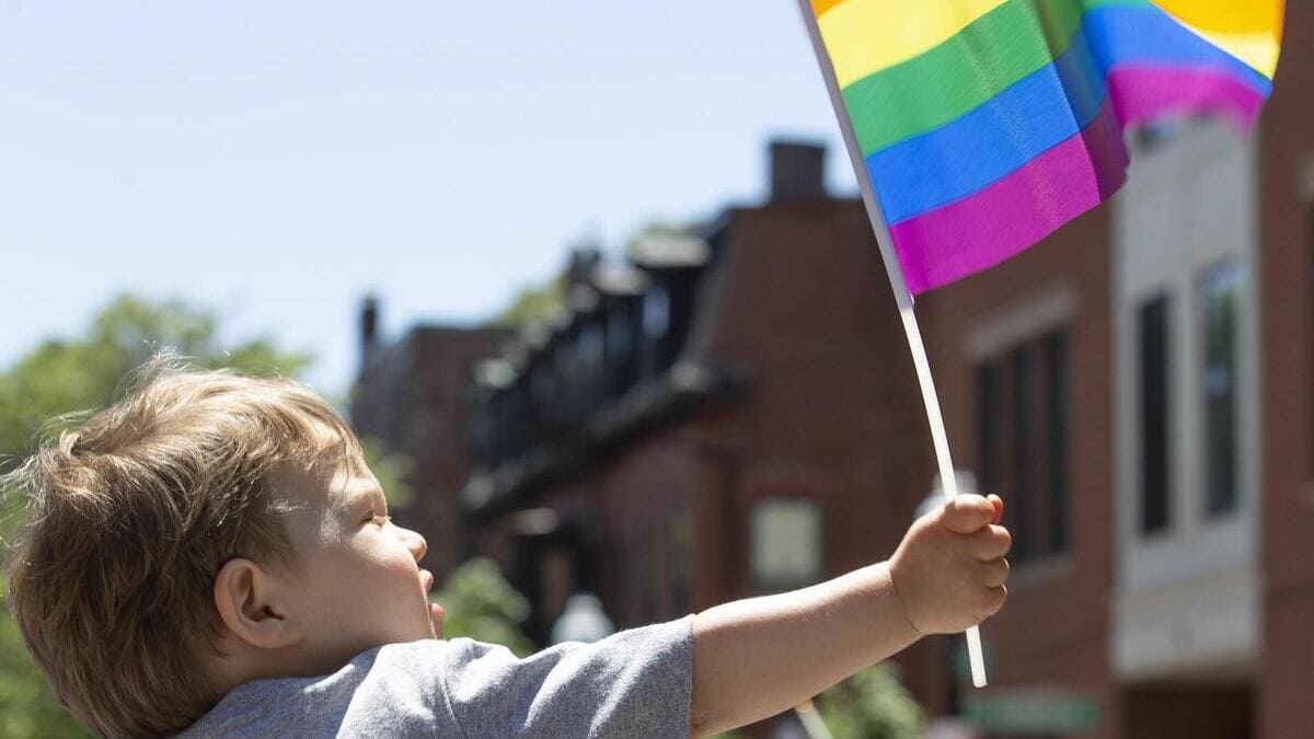 Bambino con bandiera arcobaleno al gay pride