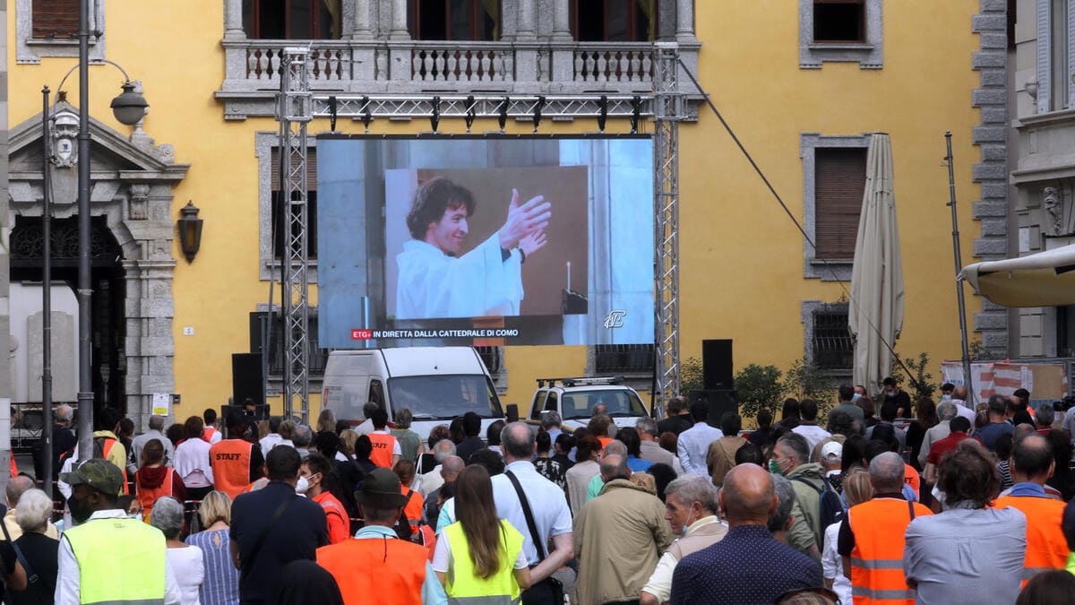 Uno dei maxi schermi allestiti nel centro di Como per permettere a migliaia di persone di seguire l'orazione funebre per don Roberto Malgesini, il parroco assassinato da uno dei senzatetto di cui si prendeva cura la mattina del 15 settembre 2020