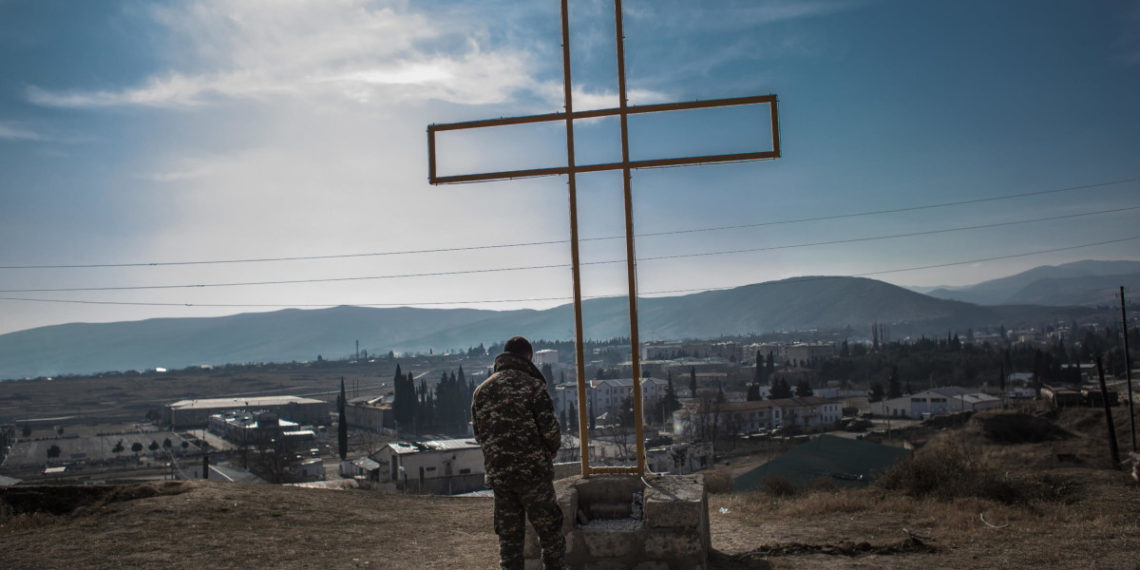 Un soldato armeno prega ai piedi di una croce in una postazione militare a Martakert, Nagorno-Karabakh