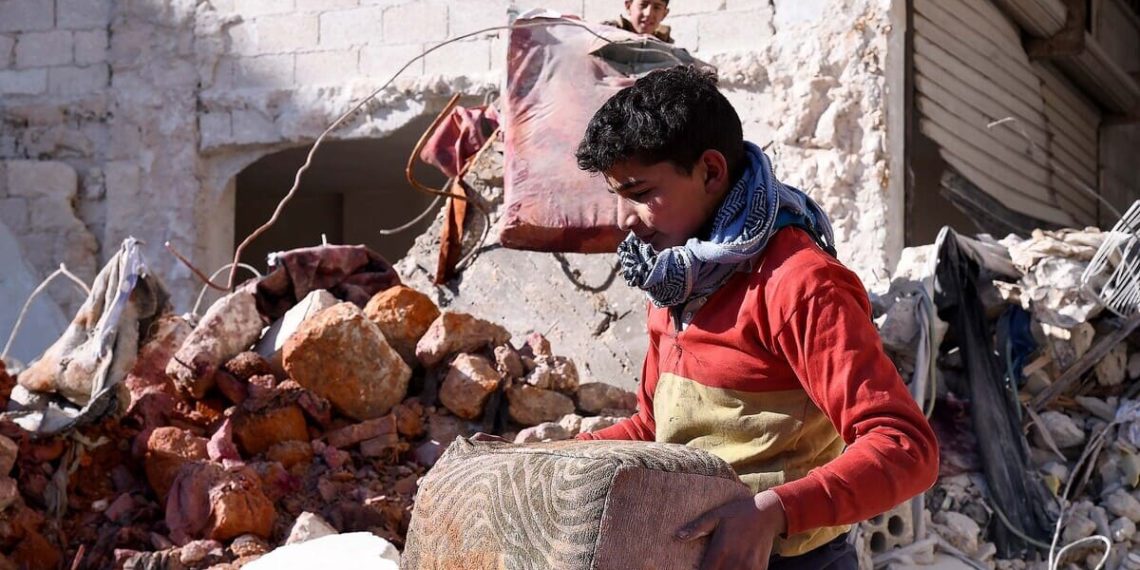 Un ragazzo ad Aleppo recupera alcuni oggetti personali dalle macerie del devastante terremoto che ha colpito la Siria