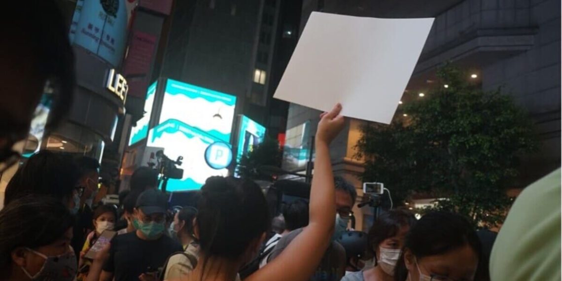 Una giovane ragazza protesta con un foglio bianco contro la censura a Hong Kong
