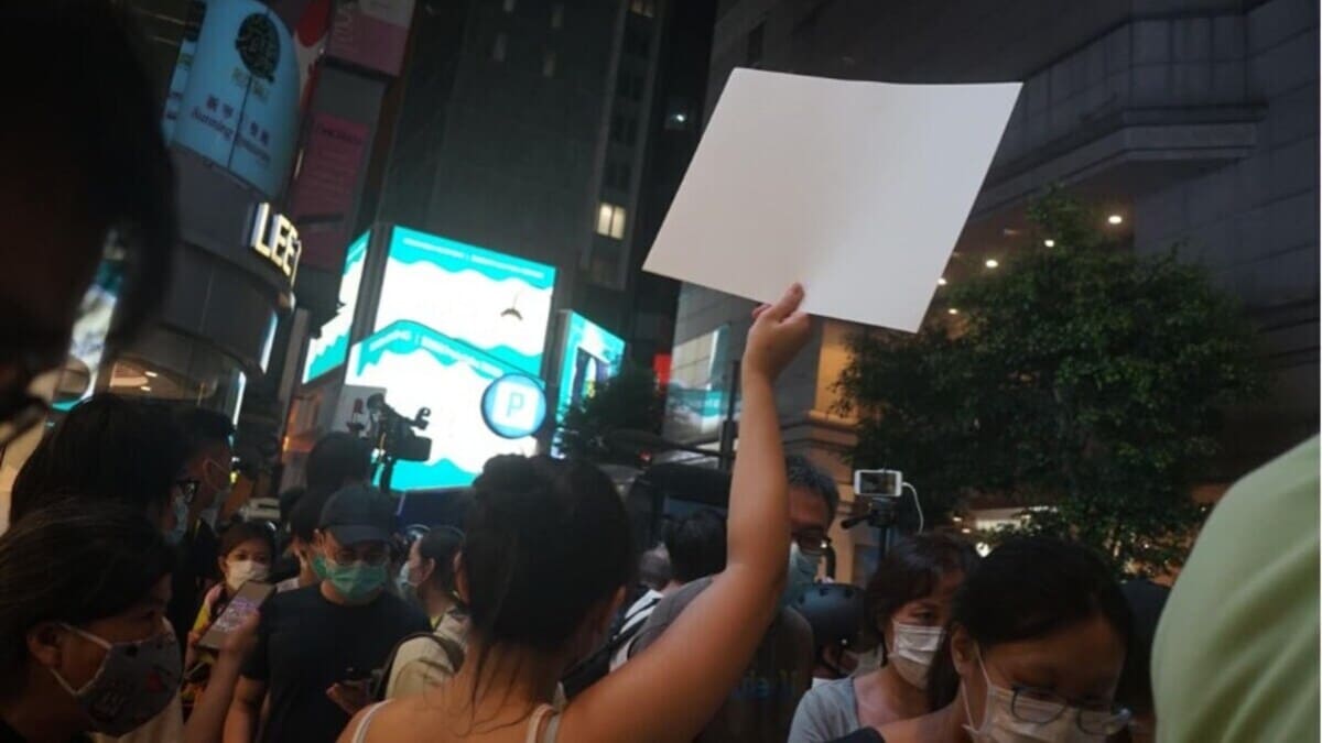 Una giovane ragazza protesta con un foglio bianco contro la censura a Hong Kong