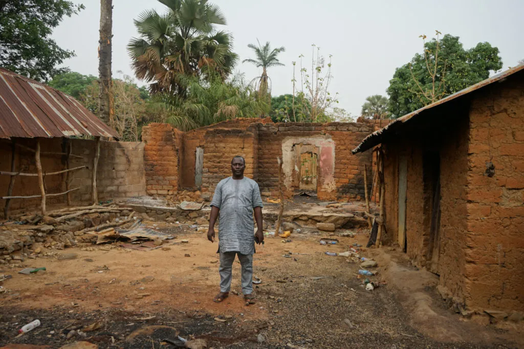 Nathan Thomas Yashim tra quel che resta della sua casa nel villaggio cristiano di Mallagum 1, Nigeria, attaccato da islamisti Fulani il 18 dicembre 2022