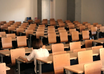 Ragazza seduta in un’aula di scuola deserta
