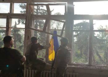 Soldati espongono la bandiera ucraina in un villaggio riconquistato dai russi