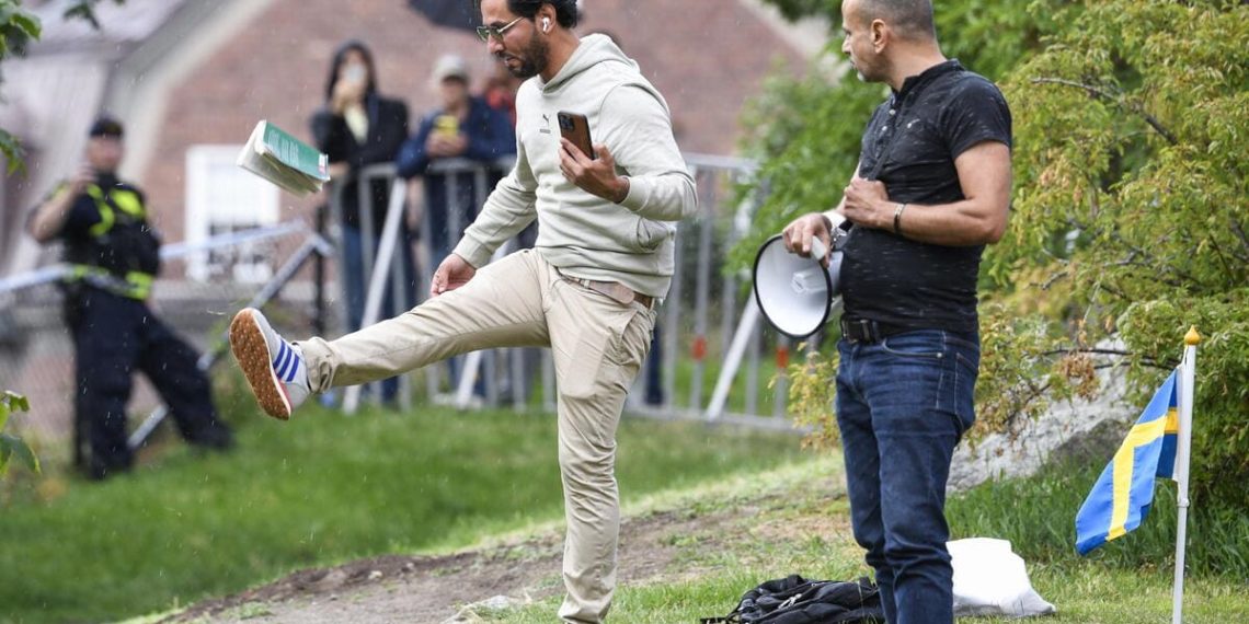 Salwan Momika colpisce una copia del Corano durante una manifestazione davanti all'ambasciata irachena a Stoccolma, 20 luglio 2023 (Ansa)