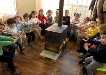 Bambini armeni in Artsakh si scaldano davanti a una stufa